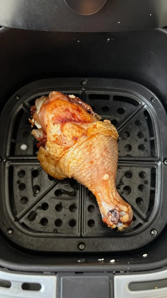 air fryer basket with single browned chicken thigh