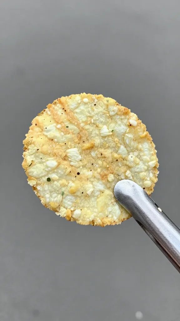 single parsley-dusted chip held by tongs