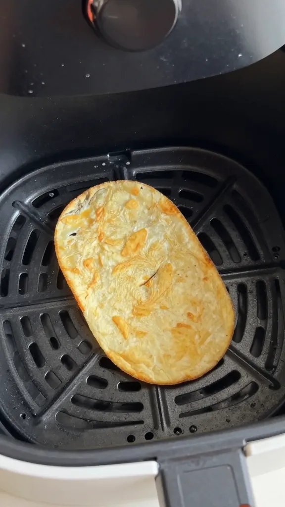 air fryer basket holding one crisp slice, shallow depth