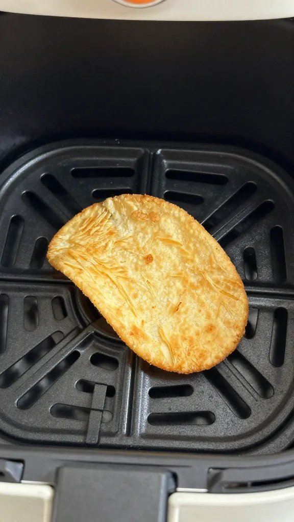 air fryer basket holding one golden crisp, closeup