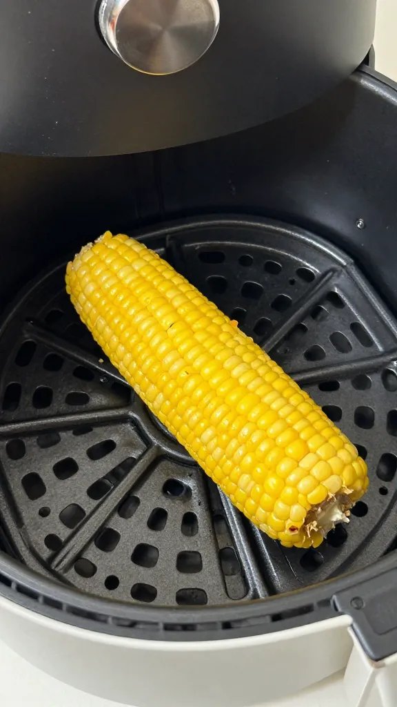 air fryer basket holding one golden corn fritter fry