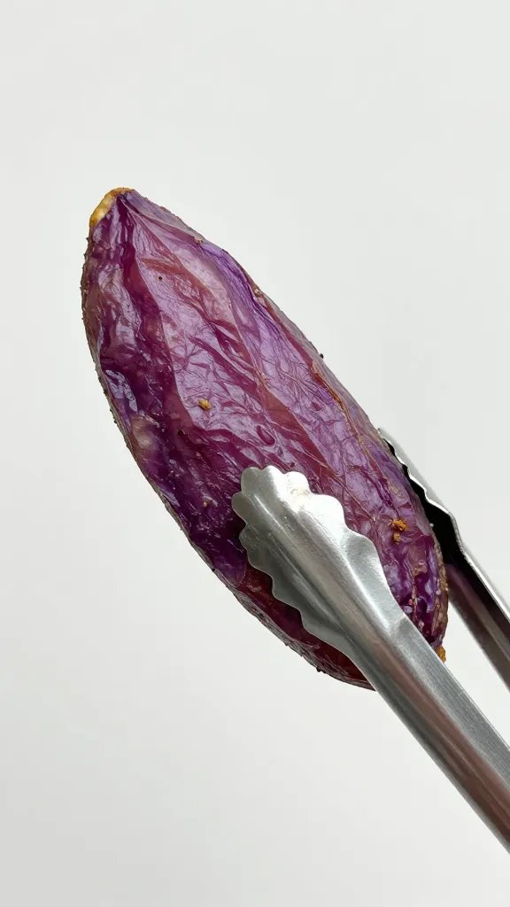 crispy purple potato wedge held by silver tongs