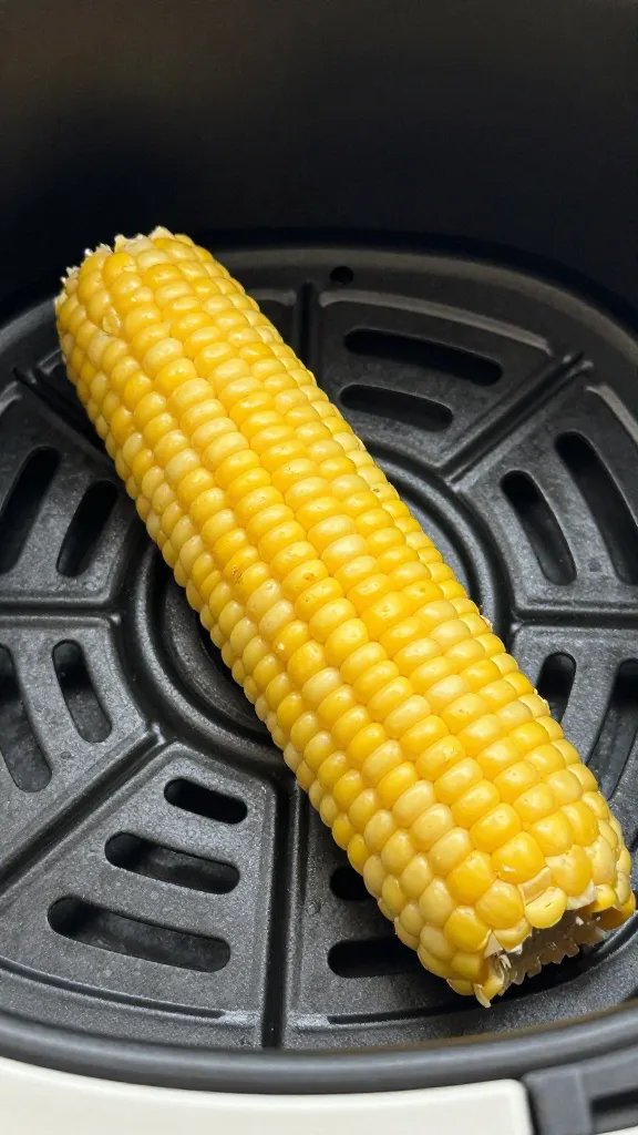 air fryer basket holding one curled corn rib, closeup