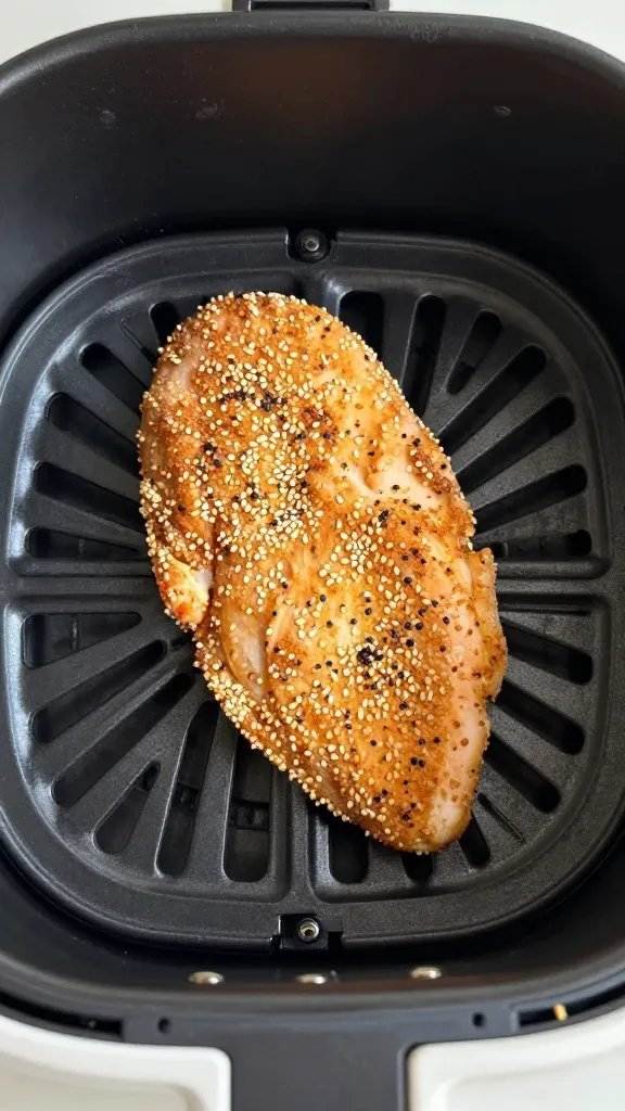 air fryer basket holding single sesame-crusted chicken breast