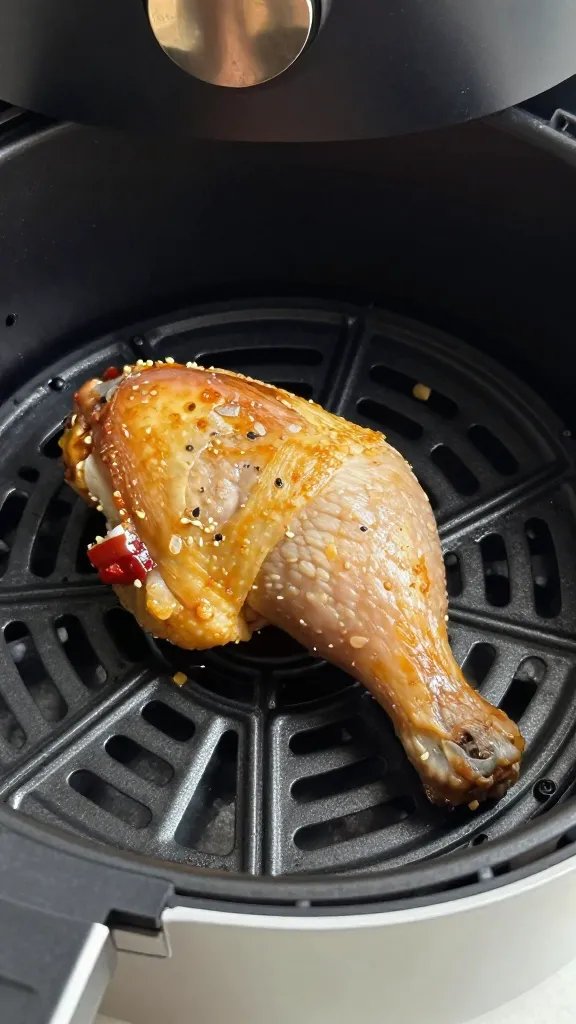 air fryer basket holding one cooked chicken thigh, closeup