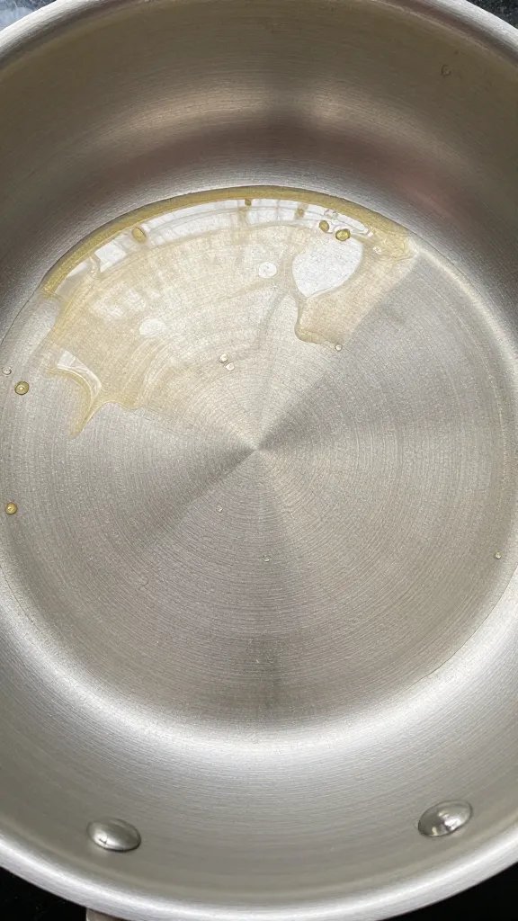 shimmering neutral oil pooling in preheated stainless skillet