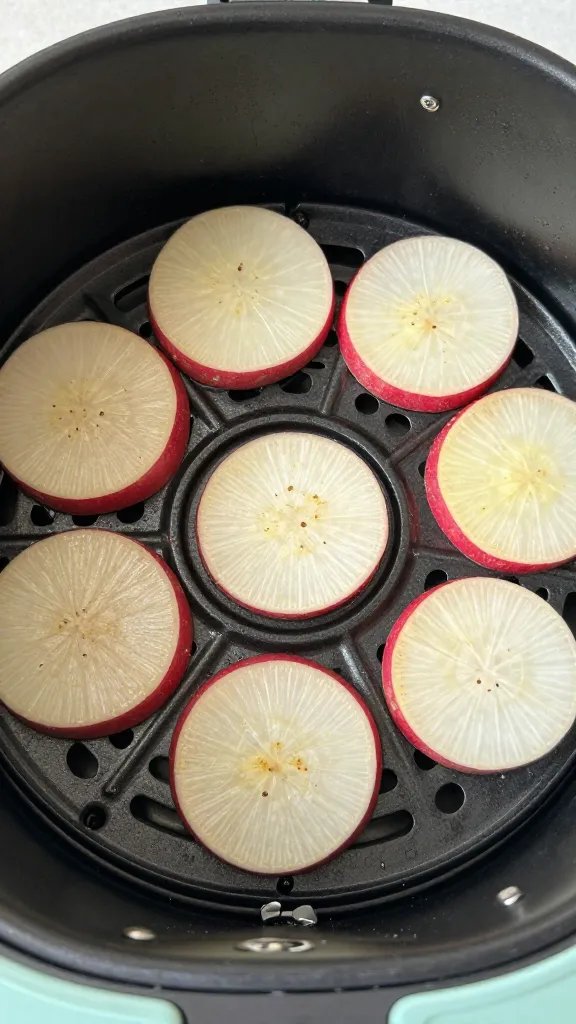 air fryer basket filled with seasoned radish slices