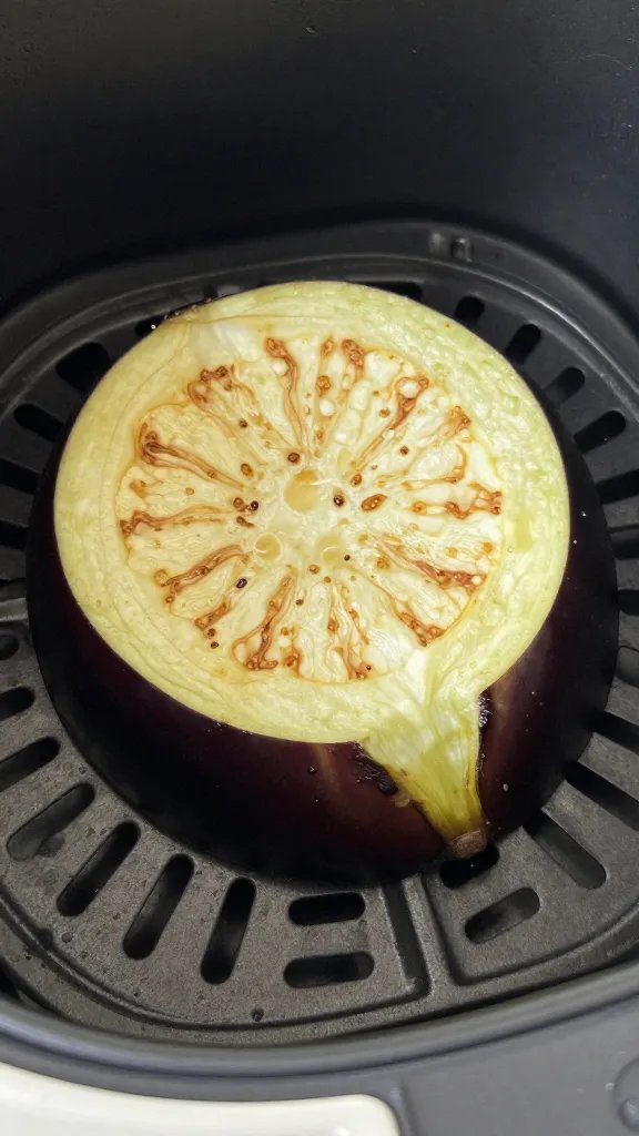 Oil-misted eggplant round in air fryer basket closeup